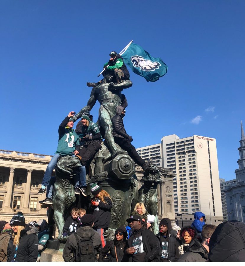 Eagles fans raise the flag on statue during parade