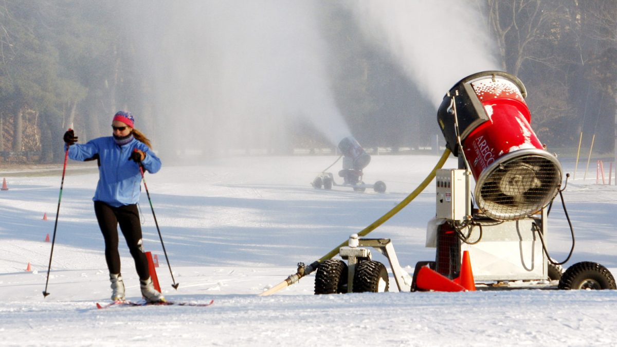 A skier glides past a snow-making machine pumping out snow in Weston, Mass., in 2010.
