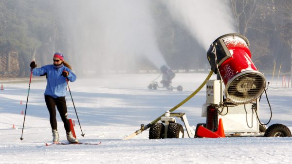 A skier glides past a snow-making machine pumping out snow in Weston, Mass., in 2010.